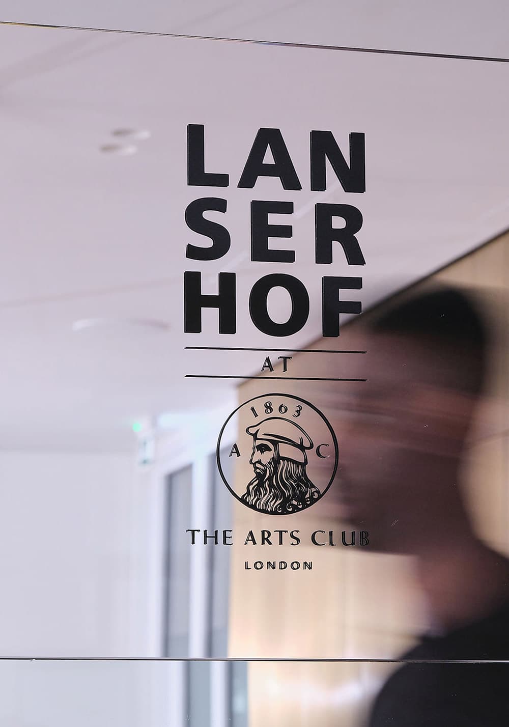 Mann vor Spiegel mit Lanserhof at the Arts Club Logo