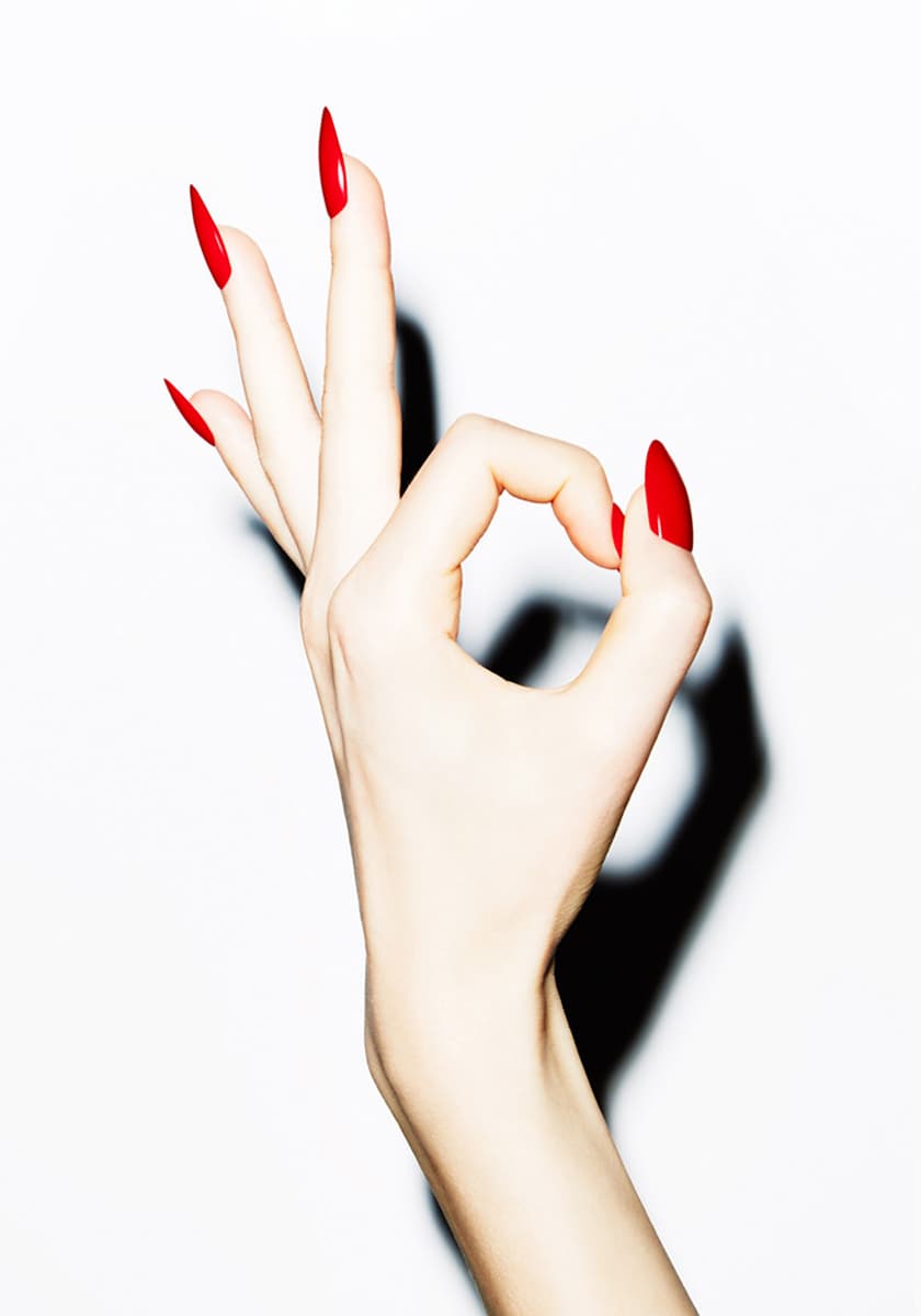 Bild einer Hand mit roten Fingernaegeln